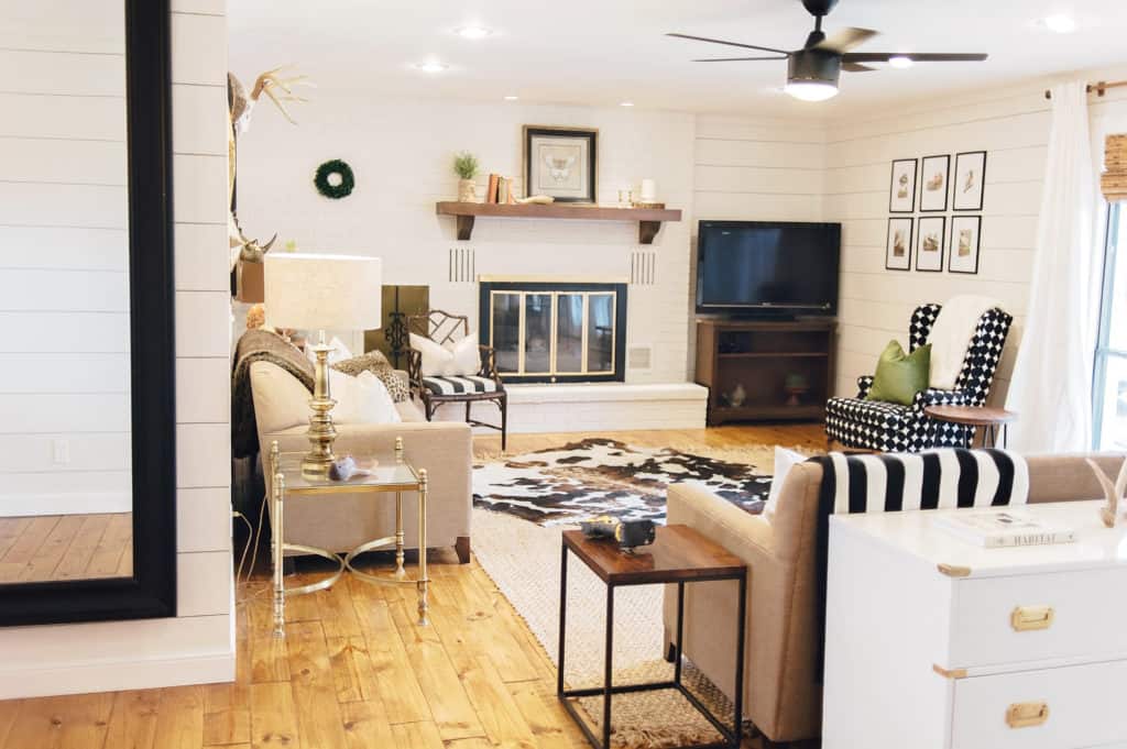 This neutral living room is far from boring with all of the textures happening! Shiplap, painted brick fireplace and layered rugs hep make this modern farmhouse living room super cozy!