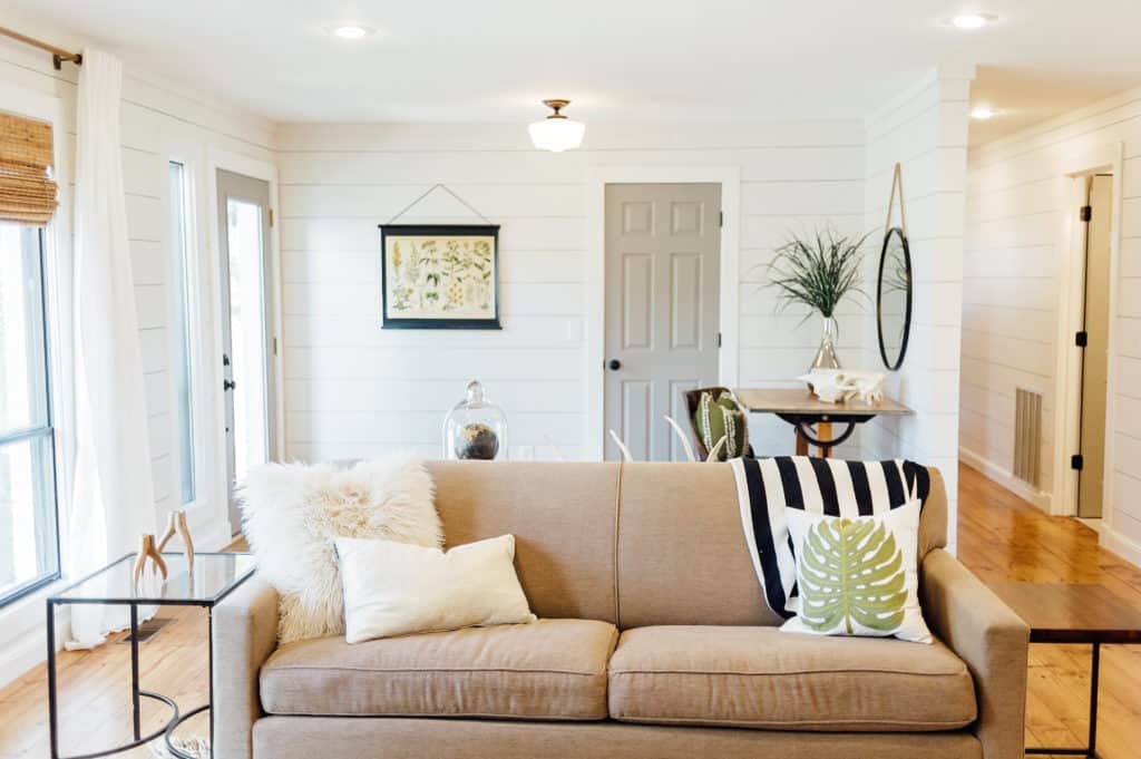 Modern Farmhouse living room. White shiplap walls and gray interior doors lend a rustic meets contemporary feeling to this renovated home.