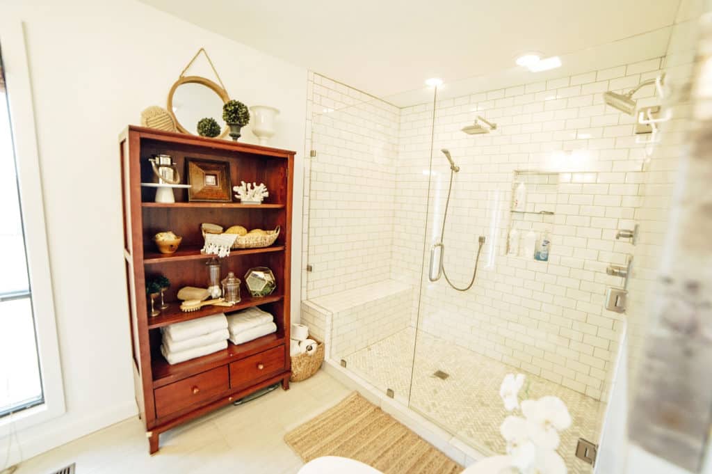 Bright and fresh master bathroom with huge walk-in shower with frameless glass doors and dual shower heads.