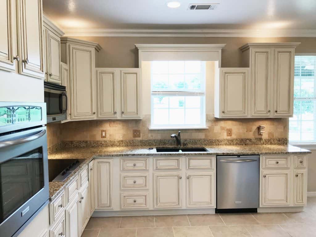 Creamy painted kitchen cabinets with brown glaze.