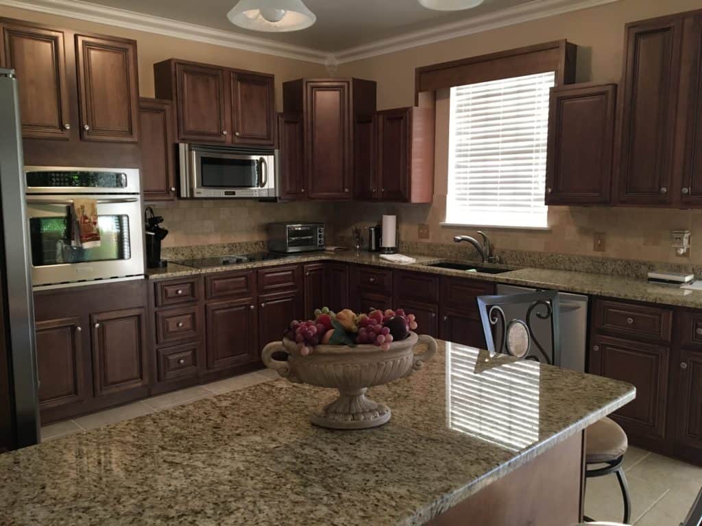 Espresso stained kitchen cabinets. Granite counter tops in updated kitchen with tumbled travertine tile backsplash