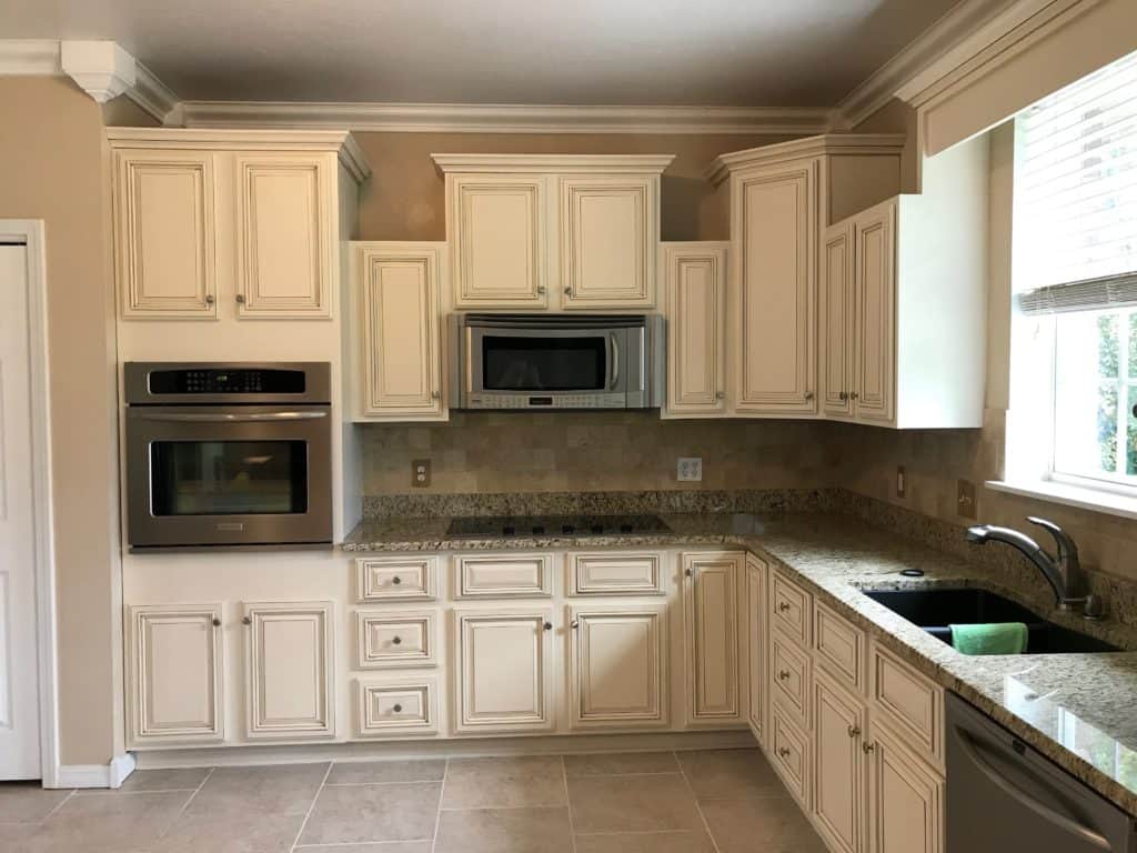 Cream kitchen cabinets with brown glaze.