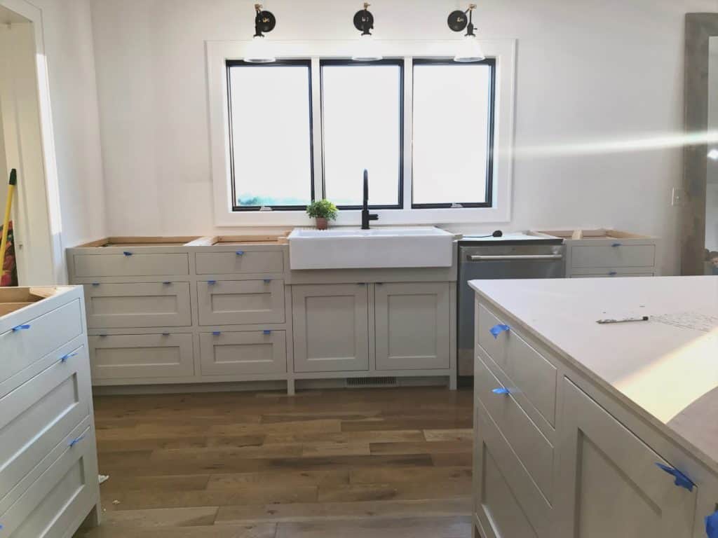Inset shaker cabinetry painted in Revere Pewter. Farmhouse kitchen sink with large window.