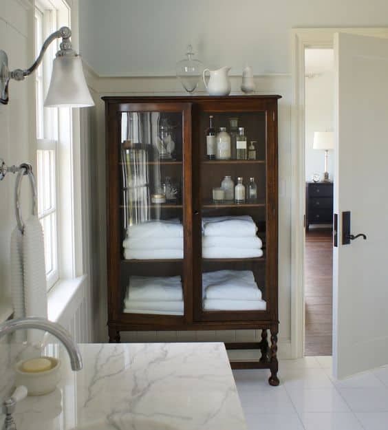 An antique glass front china cabinet is a beautiful storage option for the bathroom.