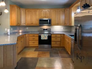 Before photo of kitchen with honey oak cabinets and walls painted sage green. Stained concrete kitchen floors