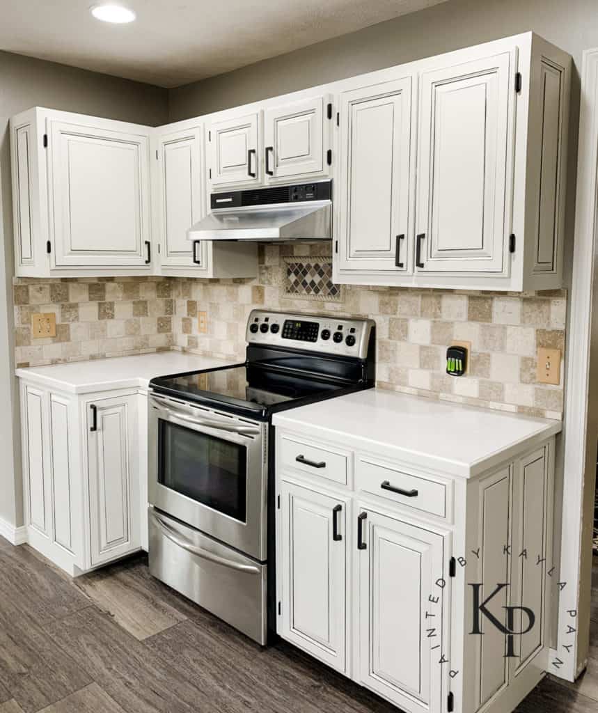 stainless steel oven with white cabinets, stainless steel appliances with painted cabinets, medium gray kitchen walls, travertine backsplash with gray grout, black hardware on white cabinets