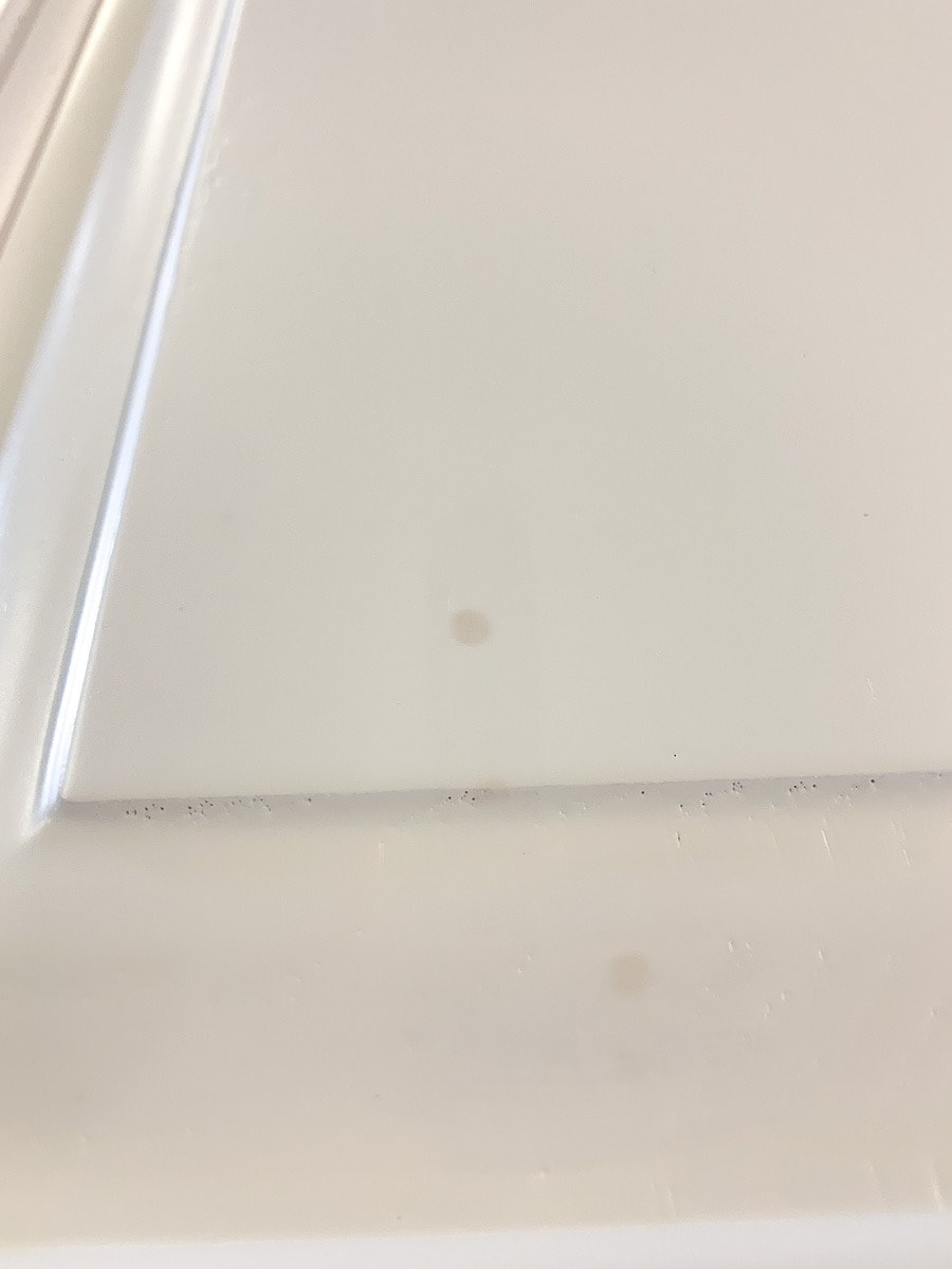 Cabinet door painted white with two small discolored spots where grease is bleeding through.