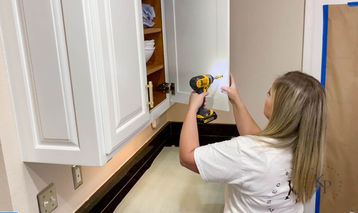 Painter re-installing kitchen cabinet doors.