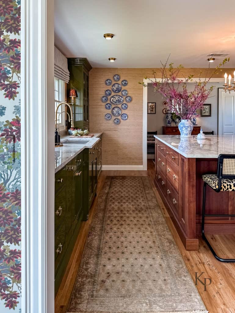 blue and white plates on kitchen wall. grasscloth wallpaper in kitchen. mahogany wood for kitchen island